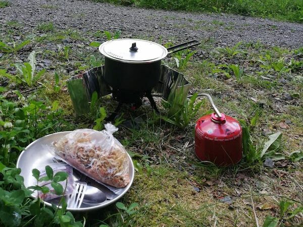 Ein Kocher und vorbereitetes Trekking-Essen stehen im Freien